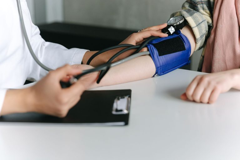 Profissional de saúde mede a pressão arterial de uma gestante em consultório médico.